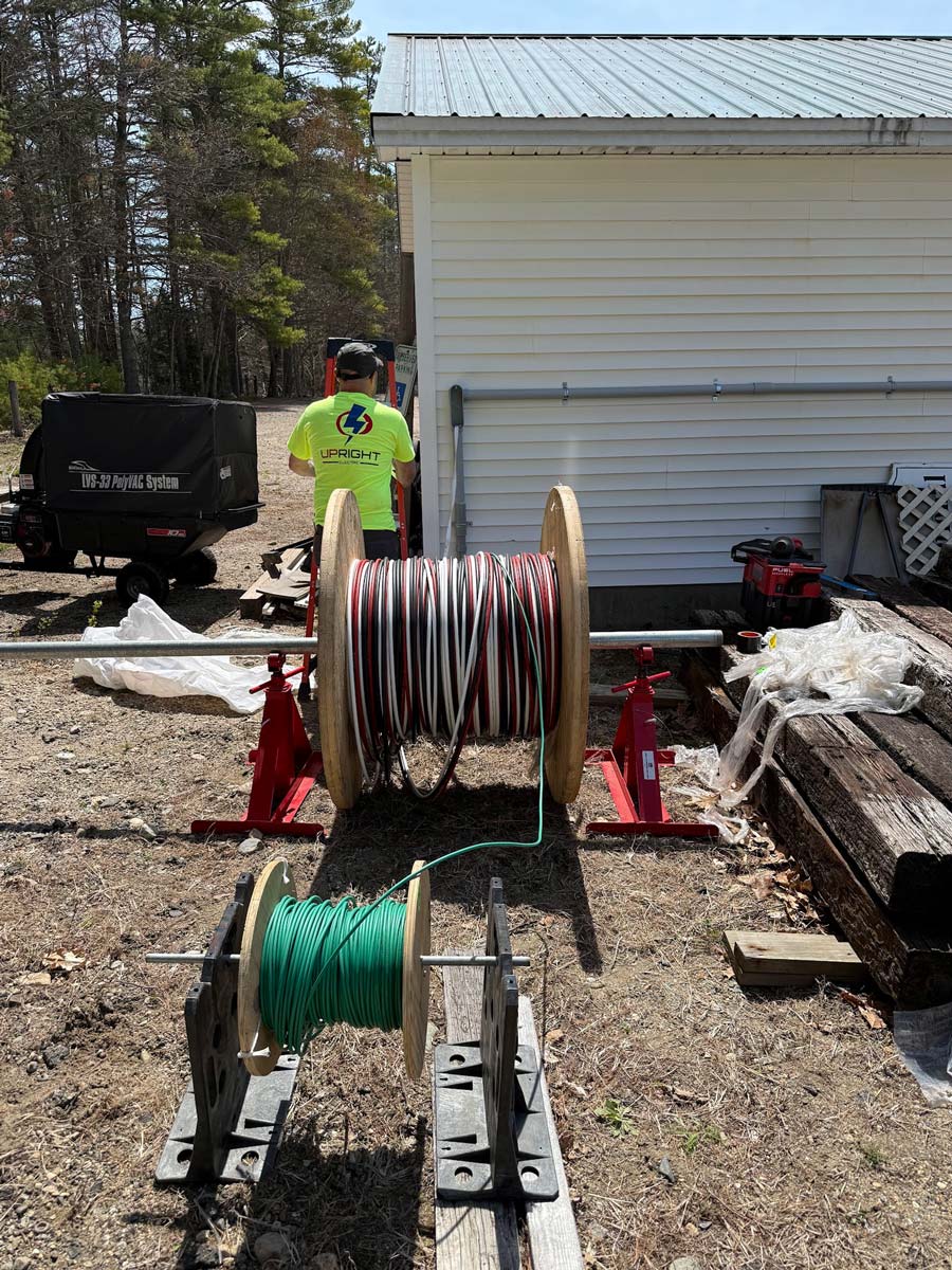 Upright Electric electrician at a commercial site with large spools of feeder cable on jack stands