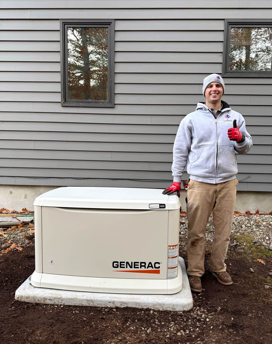 Upright Electric technician giving a thumbs-up beside a newly installed Generac Guardian 26kW standby generator