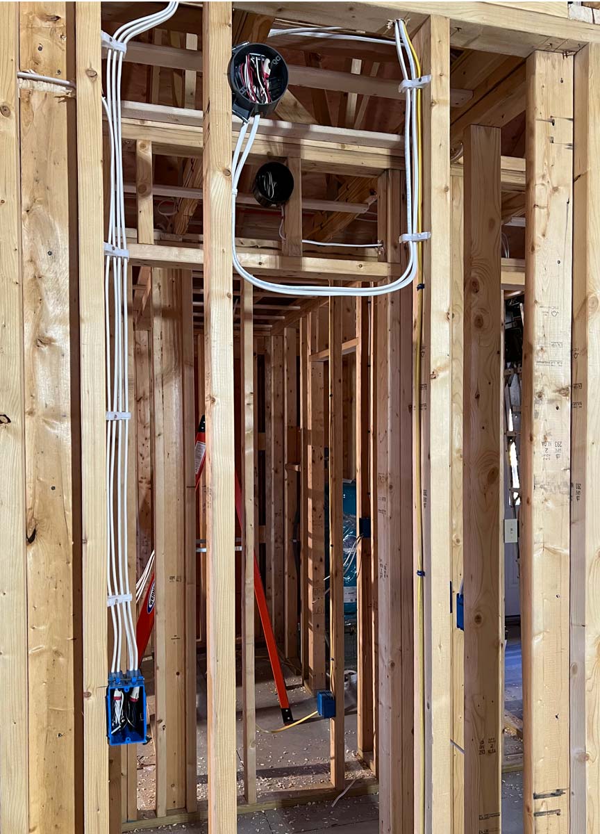 White and yellow cable and blue boxes run through open wood framing during a new-construction rough-in