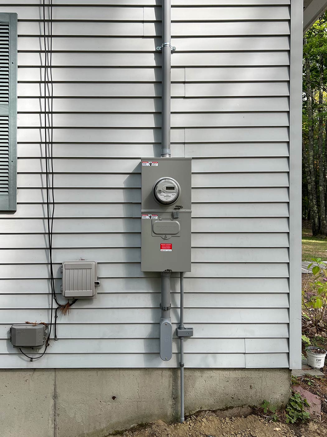 New meter socket and main disconnect with gray conduit runs on the white siding of a Meredith, NH home